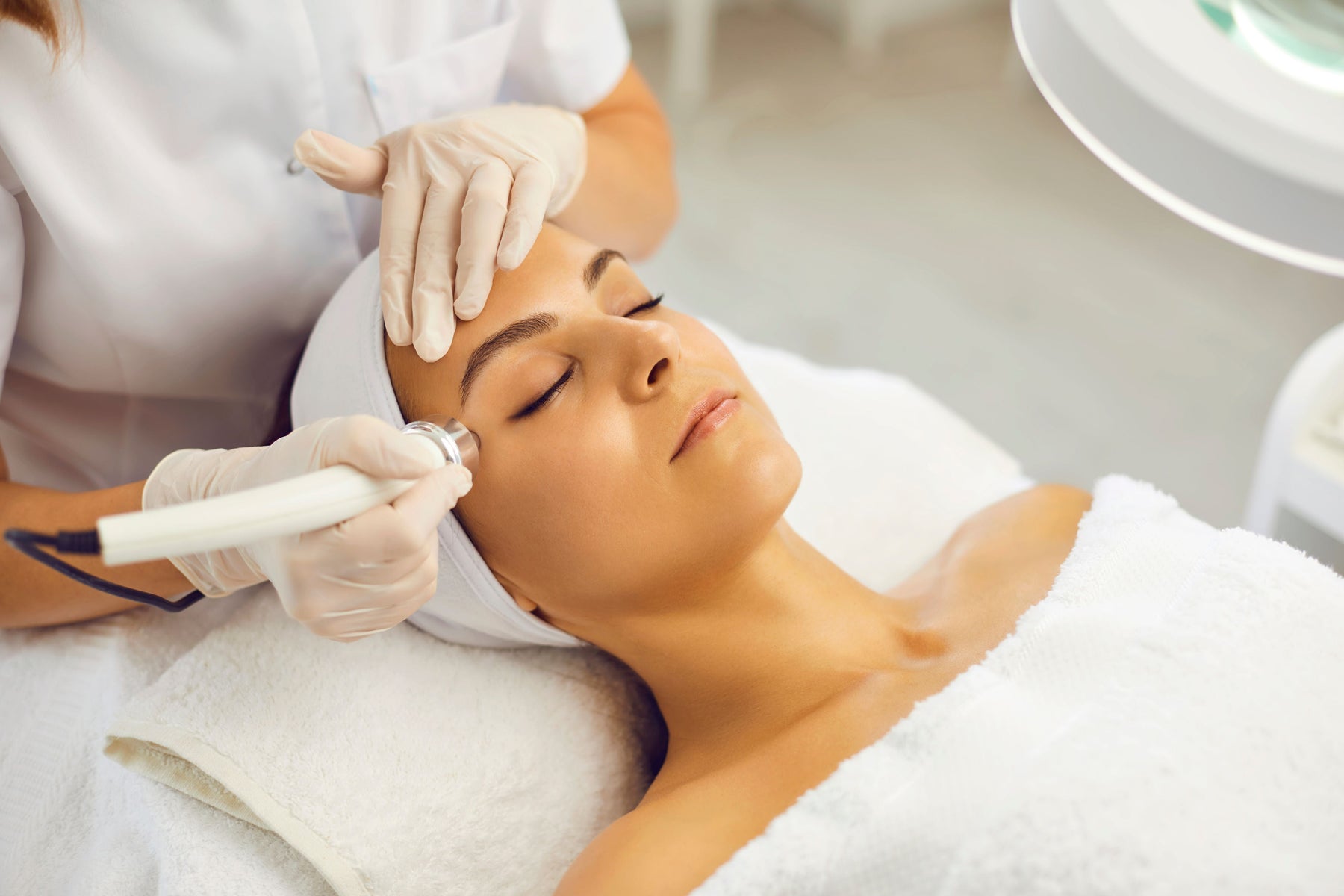 lady lying down getting electrical waves treatment on her face